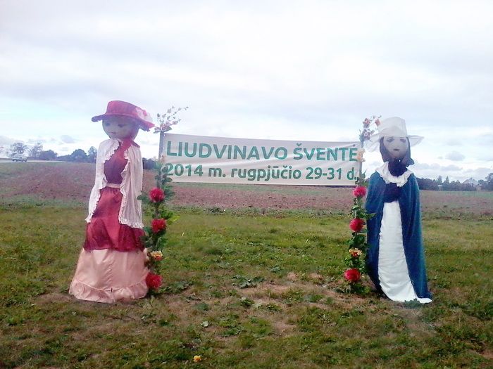 Originali Liudvinavo šventės reklama: sankryžoje pastatyta muliažinė kaimiečių pora su plakatu